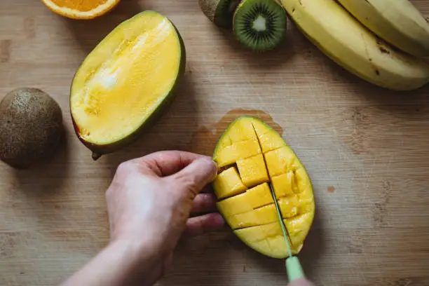 Photo of A woman cutting a mango.