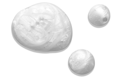 Soap or liquid cream with pearl colour on white background. Milky blobs.