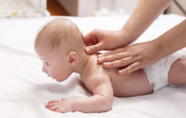 istock baby massage, close-up hands on baby back 1327235850
