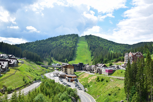 Ski resort in summer aerial view, in the background a lift to the mountainSki resort in summer aerial view, in the background a lift to the mountain. The mountain is covered with forest.