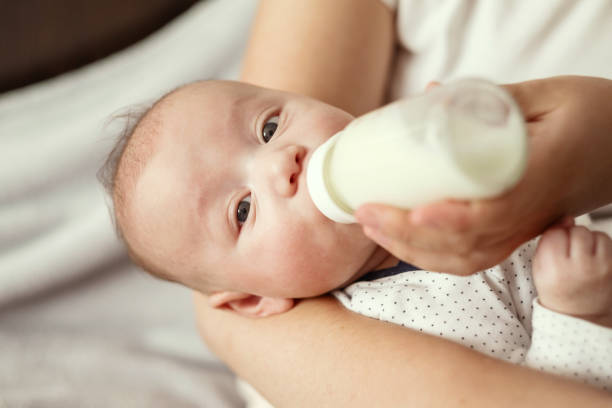 istock baby eats milk from a bottle and looks at camera 1327236596
