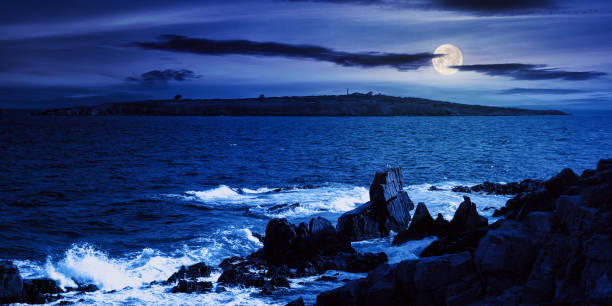 seascape at night seascape at night. wonderful scenery with island and cliffs on the shore in full moon light. clouds above horizon. fantasy travel destination in summer fantasy moonlight beach stock pictures, royalty-free photos & images