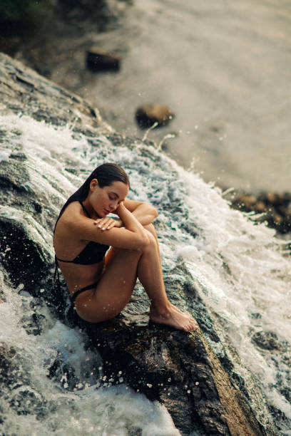 istock Woman sits under the waterfall and enjoys the falling water. 1327241687