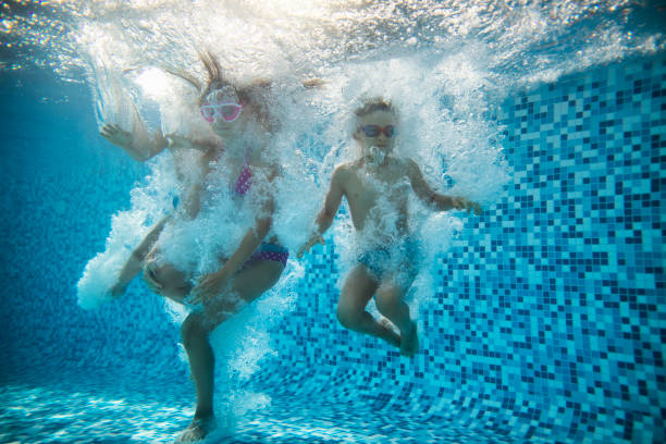 três crianças felizes pularam na piscina - bubble swimming pool water underwater - fotografias e filmes do acervo