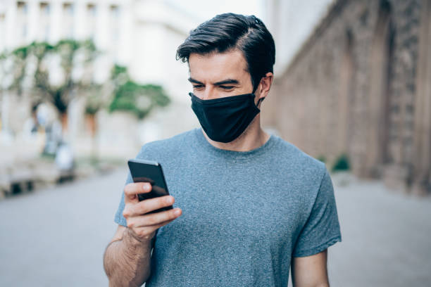 istock Man with protective mask using smartphone outdoors in the city. 1327248642