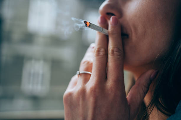jeune femme fumant une cigarette à l’extérieur. - fumée photos et images de collection