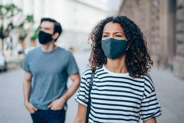 istock People with protective masks walking outdoors in the city. 1327248816