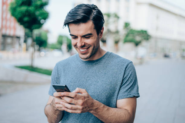 istock Young smiling man using smartphone on the street. 1327248822