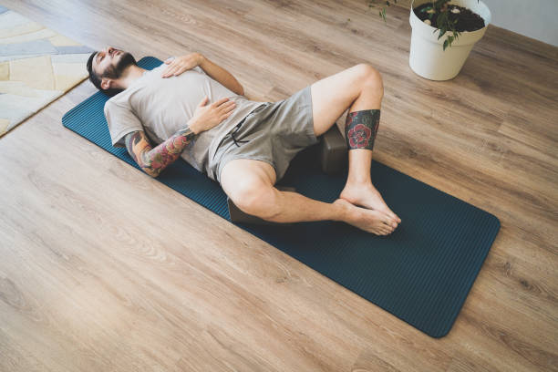 istock Young man meditating and deep breathing on yoga mat. Man doing diaphragmatic breathing exercise 1327249926