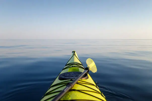 Yellow kayak with a paddle close-up in focus. The background of the sea is blurred. Active water sports.
