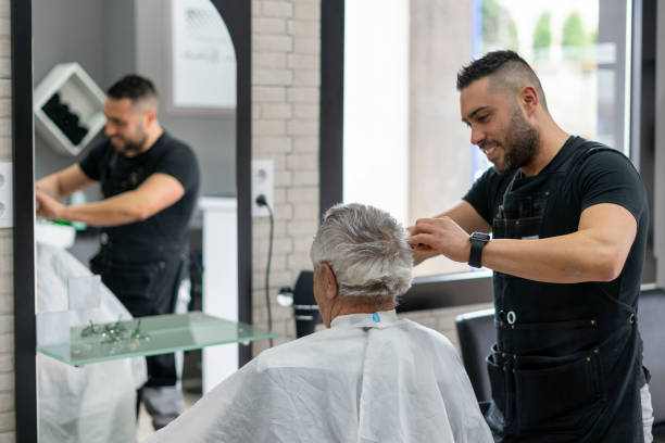 Old man cutting his hair and conversing in a barber shop stock photo