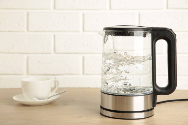 istock Glass electric kettle with white cup on grey background. 1327251443