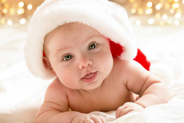 Christmas newborn baby. Little Toddler. Portrait of cute festive baby, wearing Santa hat, winter time. New Year. Cheerful kid smiling. Copyspace. Blurred Christmas lights on background. Christmas newborn baby. Little Toddler. Portrait of cute festive baby, wearing Santa hat, winter time. New Year. Cheerful kid smiling. Copyspace. Blurred Christmas lights on background. Christmas newborn baby. Little Toddler. Portrait of cute festive baby, wearing Santa hat, winter time. New Year. Cheerful kid smiling. Copyspace. Blurred Christmas lights on background. 3 months pregnant belly stock pictures, royalty-free photos & images