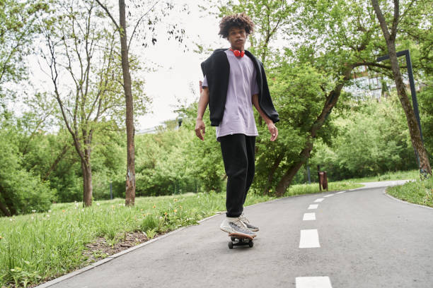 istock Man with curly hair practicing skateboarding while enjoying active rest at the urban road 1327252084