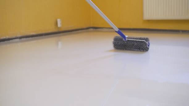 istock leveling the floor with a roller. The interior of the apartment is under construction. Self-leveling flooring. Mirror smooth floor surface. Roller application 1327252141