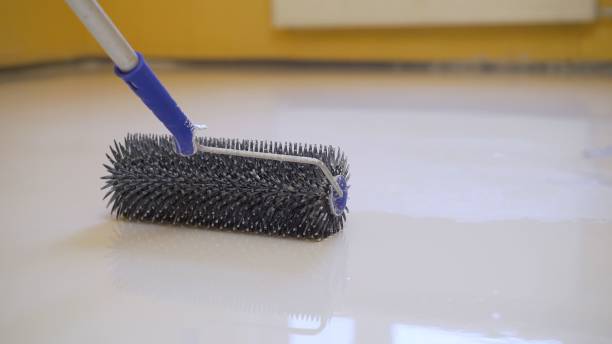 istock leveling the floor with a roller. The interior of the apartment is under construction. Self-leveling flooring. Mirror smooth floor surface. Roller application 1327252152