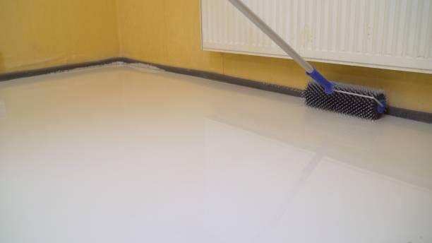 istock finishing work - a working roller primers the floor before pouring the floor. Workers poured into the bulk floor 1327252219