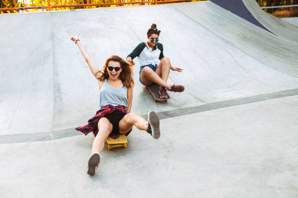 dos chicas jóvenes alegres divirtiéndose - monopatín actividades recreativas fotografías e imágenes de stock