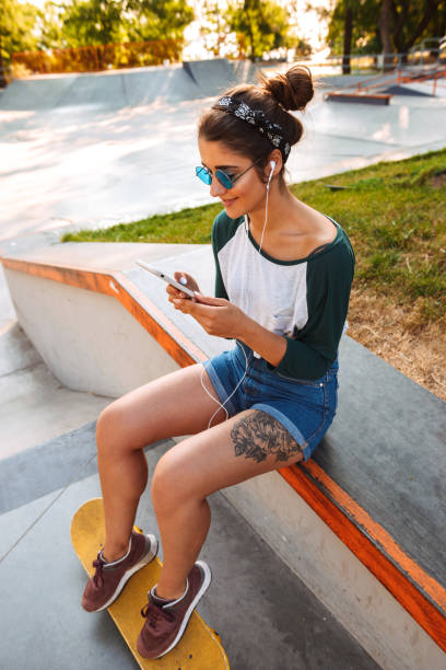 istock Cheerful pretty woman sitting outdoors with skateboard 1327255723