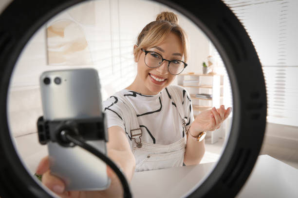 istock Blogger recording video at home, view through ring lamp 1327255940