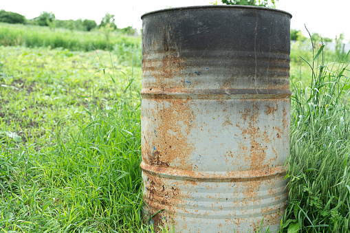 old rusty metal barrels and a stove in the backyard of a rural house close-up on the grass for scrap metal and for incineration of garbage disposal