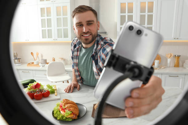 istock Blogger preparing for video recording in kitchen at home. Using smartphone and ring lamp 1327256288