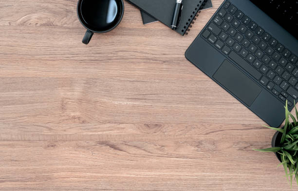 istock Flat lay of black tablet keyboard, coffee cup and notebook on wooden table with copy space. 1327257714