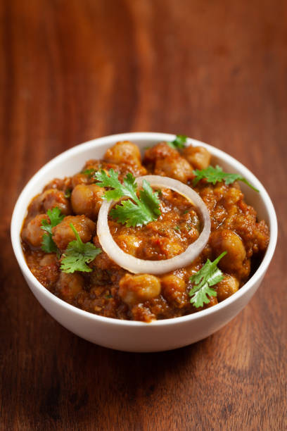 istock Chickpeas masala (Spicy chola or chhole curry)  garnished with fresh green coriander and ingredients. A Classic Indian typical Punjabi street food. 1327259946