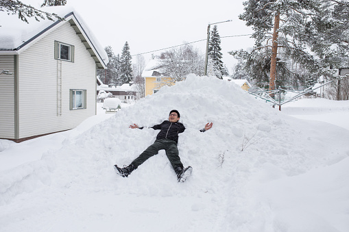 Asian Chinese traveler to Nordic country lying in the snow happily.