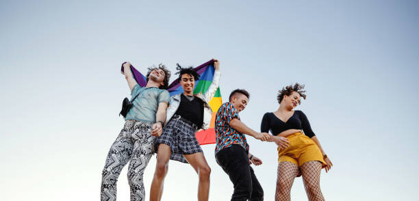 fröhliche gruppe queerer individuen, die zum stolz tanzen - homosexual gay man parade flag stock-fotos und bilder