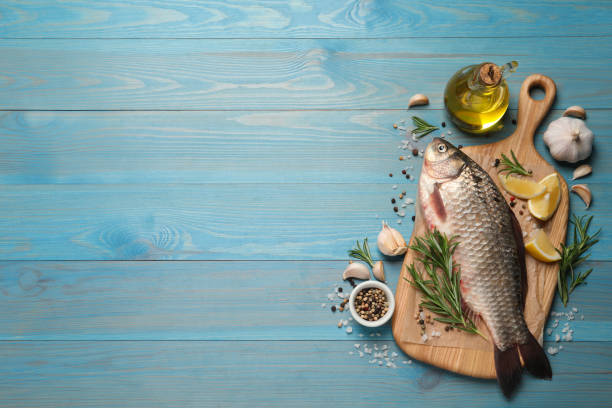 istock Fresh raw crucian carp and ingredients on light blue wooden table, flat lay with space for text. River fish 1327266732
