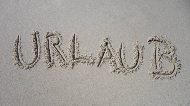 Word Holidays german "Urlaub" written in Sand stock photo