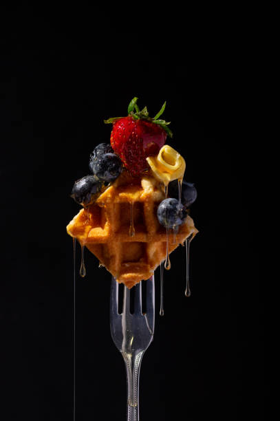 belgische waffel mit erdbeere, heidelbeeren und butter auf einer gabel, gekrönt mit honigtropfen. - waffle syrup pouring breakfast stock-fotos und bilder
