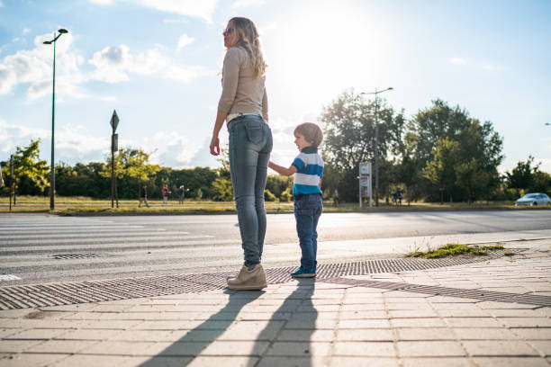 Mother and son crossing the road Mother is learning her son how to cross the road crossing sign stock pictures, royalty-free photos & images