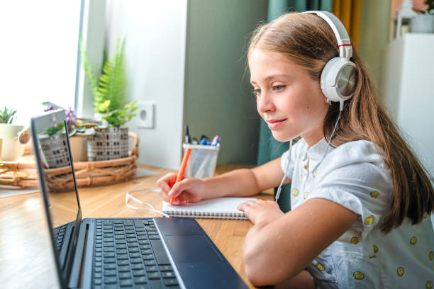 istock Beautiful little girl at home learning using a laptop computer, learning through an online e-learning system 1327273597