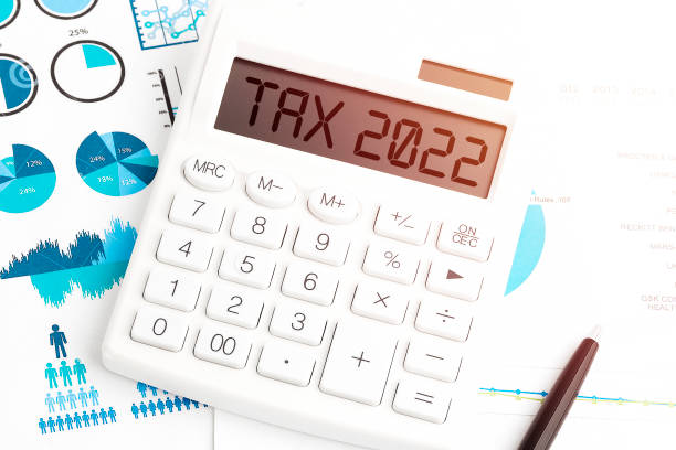 istock Text TAX 2022. Calculating machine, pen and charts, documents and graphs top view. Business and tax concept on white background. 1327275366