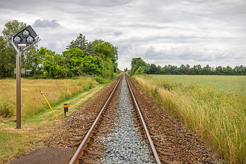 Single track railroad crossing through agricultural fields at Lolland, an remote part of Denmark which are famous for its flat landscape