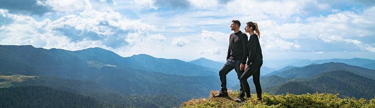 The happy couple standing on the mountain with a picturesque cloudscape