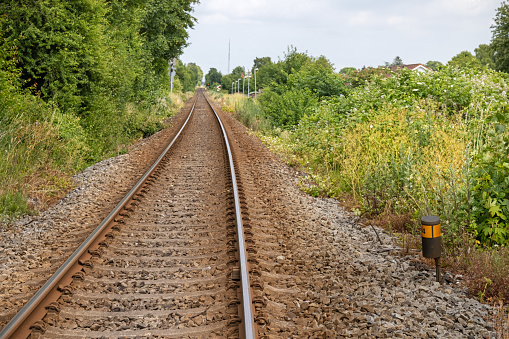 Single track railroad crossing through an area with low trees to take away the sound of the passing trains in Lolland an remote area of Denmark famous for its flat landscape