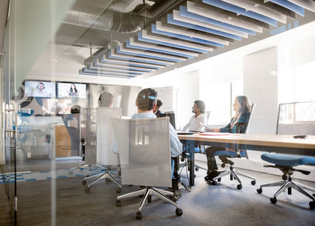 Business team having video conference in office Business team sitting inside conference room and having a video conference in office video conference stock pictures, royalty-free photos & images