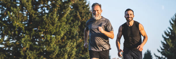 el padre feliz y un hijo corriendo en un camino del parque - sports clothing practicing success vitality fotografías e imágenes de stock