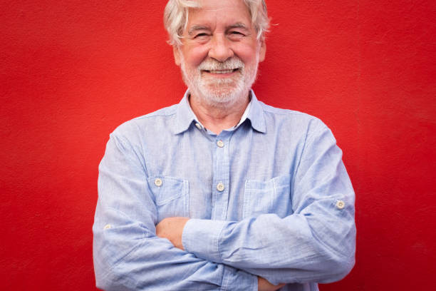 istock Handsome man with crossed arms standing on red background, smiling happily looking at camera, caucasian senior people with white beard and hair 1327279465