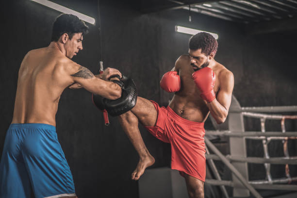istock Young dark-haired kickboxer working on his leg kick with a coach 1327280681