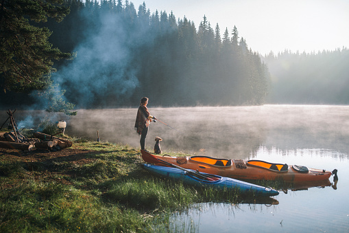 Landscape photo, woman fishing in the morning during camping in the mountain lake.