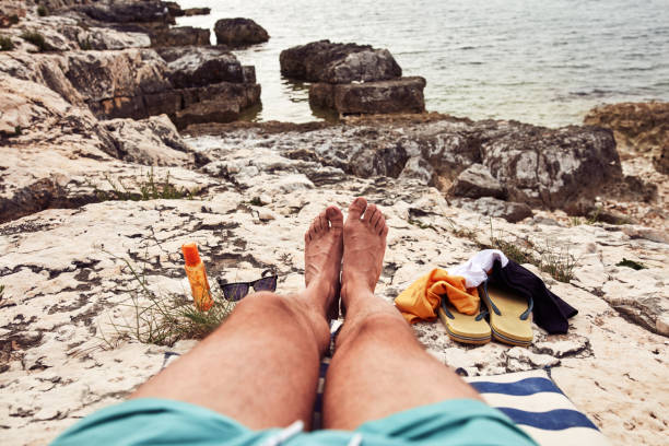 Man sunbathing on a rocky sea ocean beach.