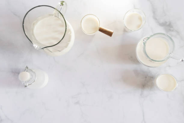 milk drinks in clear jars and glass of milk on marble table background. healthy drink concept. - dairy farm liquid food and drink splashing imagens e fotografias de stock