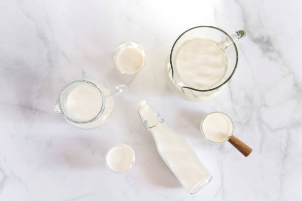 milk drinks in clear jars and glass of milk on marble table background. healthy drink concept. - dairy farm liquid food and drink splashing imagens e fotografias de stock