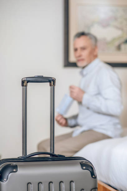 istock Gray-haired mid-aged man with a protective mask in a hotel room 1327285798