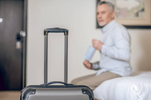 istock Gray-haired mid-aged man with a protective mask in a hotel room 1327285847