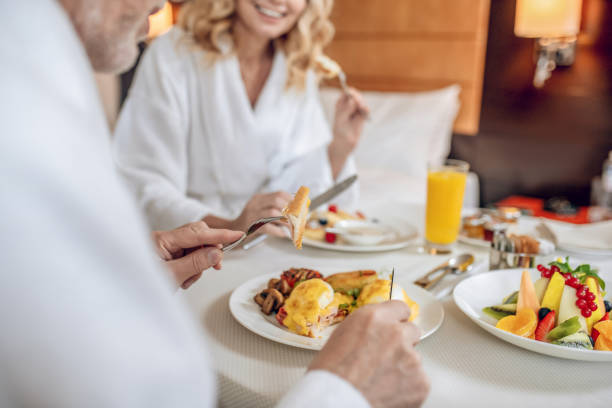 ein paar in weißen roben beim frühstück und zufrieden aussehen - zimmerservice stock-fotos und bilder